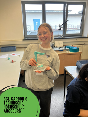 Forscherinnen-Camp bei SGL Cabon und Technische Hochschule Augsburg Titelbild Instagram-Reel: Ein Mädchen hält eine gebaute Handyhalterund aus Carbon