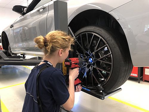 Ein Mädchen montiert Reifen am Auto